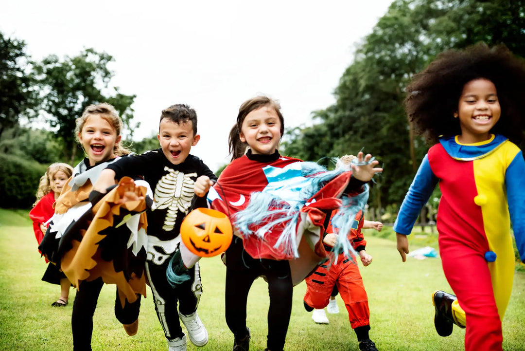 Group of children in Halloween costumes enjoying outdoor play, reflecting Herbal Goodness Kids Line.