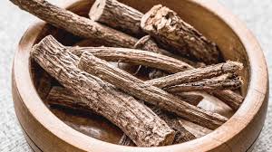 Dried licorice root pieces in a wooden bowl for skin conditions and digestive comfort.