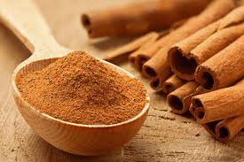 Wooden spoon of ground cinnamon showing health benefits for blood sugar levels.